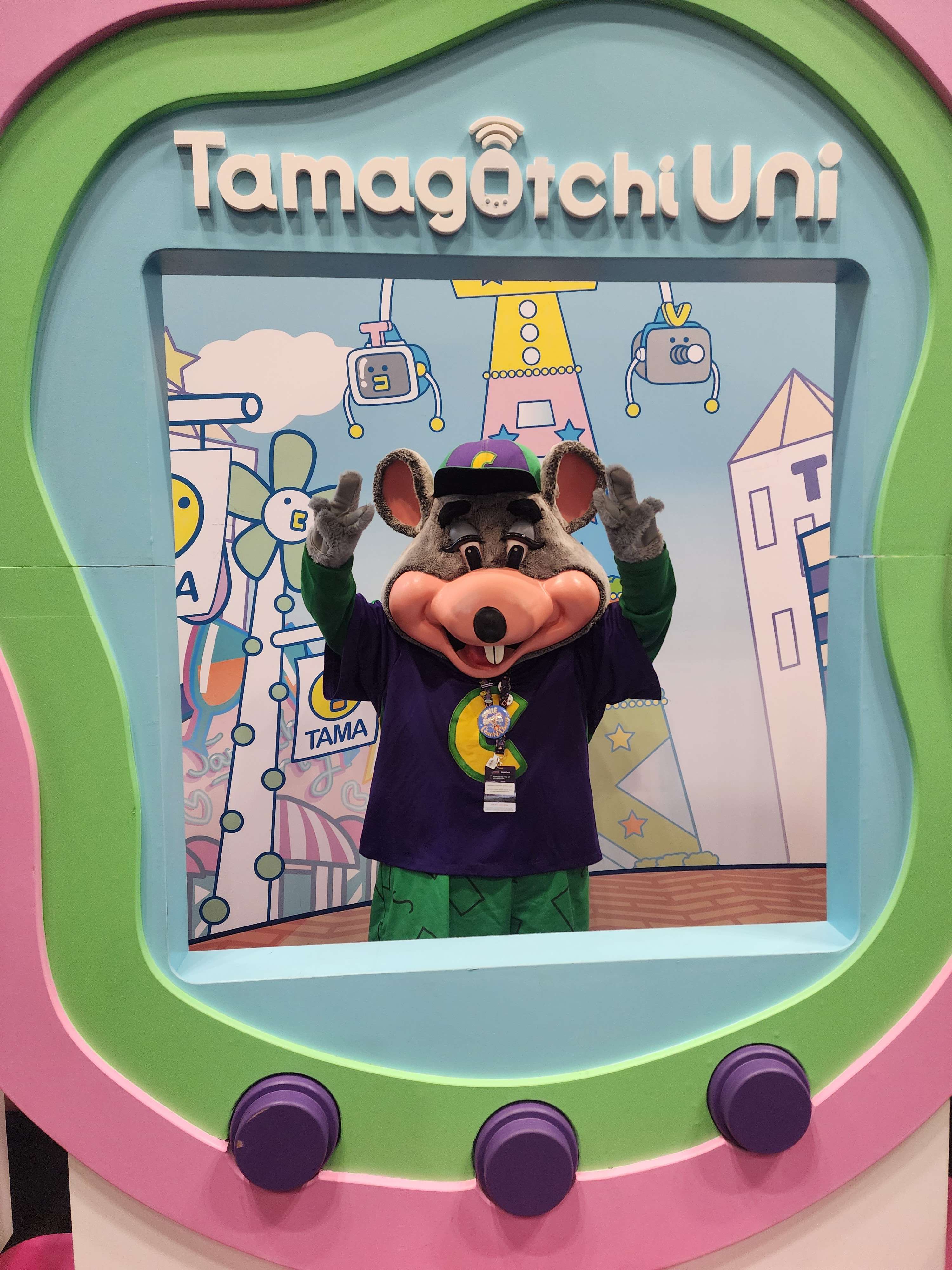 me wearing my chuck walkaround at new york comic con 2023. i'm standing at a tamagotchi themed photo op frame, with my hands raised by my head doing peace signs.